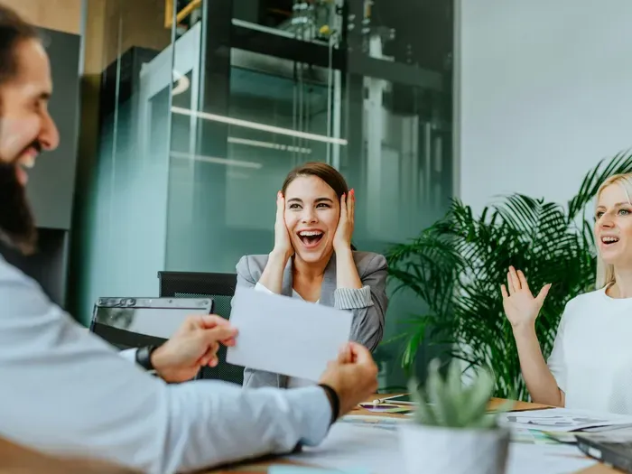 Group of coworkers celebrating success at a meeting table with joyful expressions, featured on towndirectorynethub.com